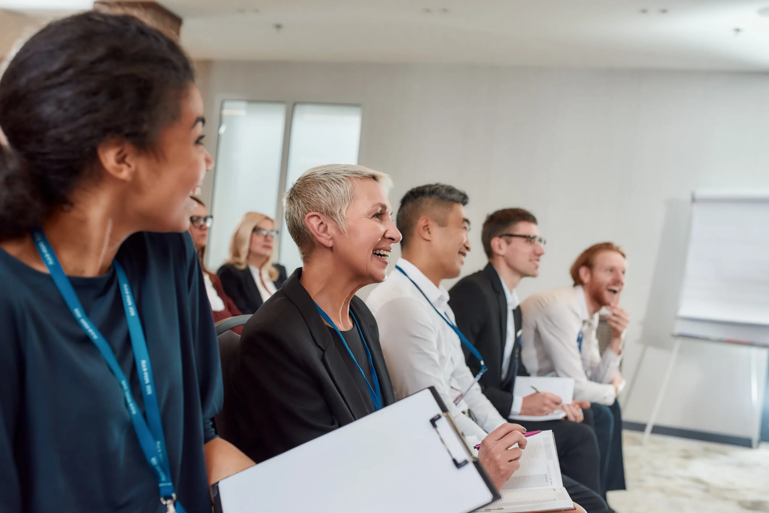ci sono delle persone a un convegno che sono felici di ascoltare mentre prendono appunti